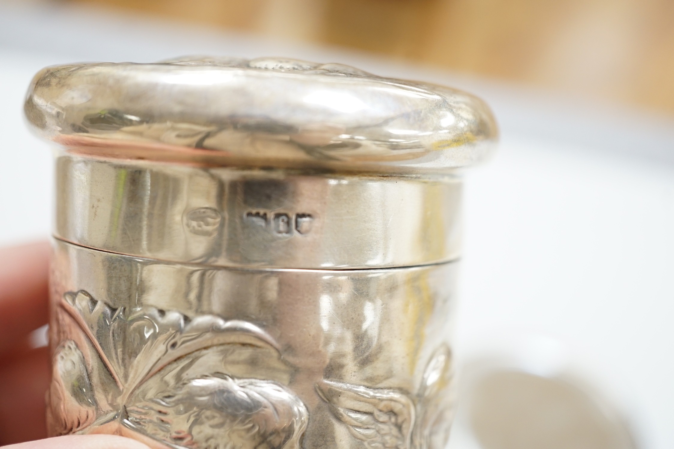 An Edwardian repousse silver Reynolds Angels toilet jar and cover, by William Comyns, London, 1901 and a later similar hand mirror by William Neale Ltd.